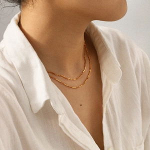 Gros plan sur un collier double rang en acier inoxydable doré avec détails de perles