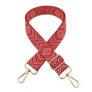 Dettaglio tracolla intrecciata rossa e bianca con motivi geometrici e fibbie d'oro