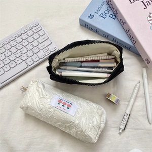 Detail of quilted pencil cases in black and white with flower tag and zipper closure