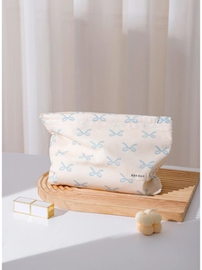 Minimalist beige cotton makeup bag with blue bow prints on a wooden decorative tray