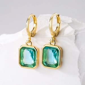 Luxurious 18K gold plated drop earrings with emerald-cut turquoise stones on stone background