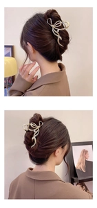 Model wearing a large golden metal bow hair claw clip with a pearl accent from behind