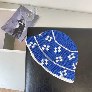 Detail of blue crochet bucket hat with white flower patterns on leather surface