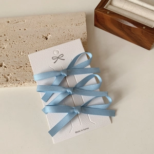 Detailopname van drie blauwe kanten haarstrikjes bij een minimalistisch juwelendoosje
