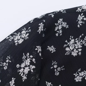 Close-up of black floral chiffon fabric showing delicate white print and fine stitching