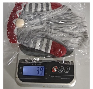 Detailed view of knitted Santa wine bottle cover on a scale weighing 39 grams