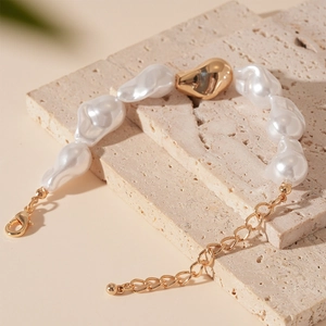 Détail du bracelet en perles baroques avec billes dorées sur une surface en pierre