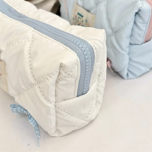 Detail of quilted waterproof pencil case with pearl finish and blue bow accent