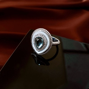 Detailed macro shot of a blue teardrop stone ring with twisted silver rope band on silk