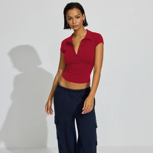 Detail of red slim fit polo crop top with button collar and navy cargo pants