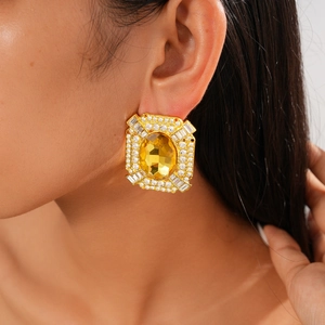 Gros plan de boucles d'oreilles vintage dorées avec pierre jaune et accents de diamants