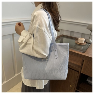 Detail of light blue tote bag featuring pleated texture and metallic butterfly knot