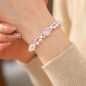 Dettaglio del bracciale di perle a due file con un grande zircone rosa sul polso di una modella