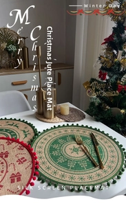 Detailed view of jute Christmas placemats featuring festive reindeer prints and pom-pom trim