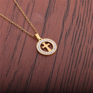 Detail of a gold stainless steel necklace featuring a crystal-set circular cross pendant