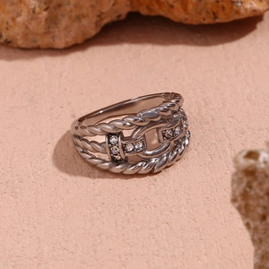 Macro detail of silver chain-style ring with sparkling stones on textured surface