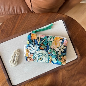Detail of floral printed bag featuring a green woven zipper pull and woven brand label
