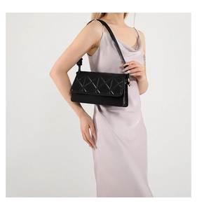 Close-up of black quilted shoulder bag with geometric pattern on satin dress model