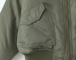 Detailed macro view of army green bomber jacket with metal zipper and flap pocket texture