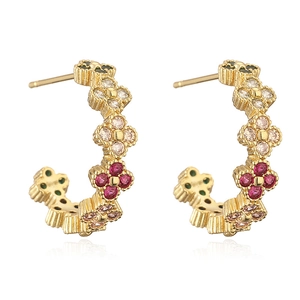 Macro view of gold C-shape clover earrings with pink, green and white crystals