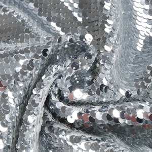 Close-up of sparkling silver sequin fabric with elegant spiral draping and luxury texture