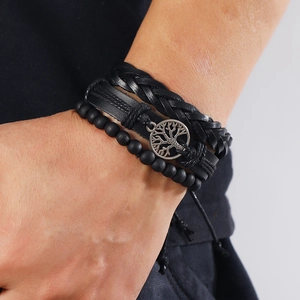 Detailed view of black braided leather bracelet set featuring a silver tree of life charm