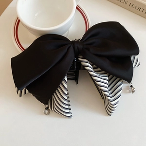 Détail d'une grande pince à cheveux en satin noir avec tissu rayé et perles élégantes
