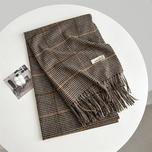 Detail of classic brown and orange houndstooth scarf featuring elegant fringe and woven tag