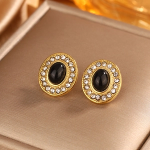 Macro shot of vintage gold-plated oval stud earrings with black stone and pavé zircons