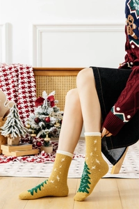 Detail of yellow Christmas tree socks in thick coral fleece on a cozy background