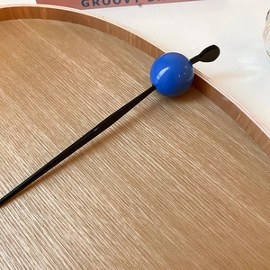 Minimalist geometric hair pin with a bright blue sphere detail on a wooden tray