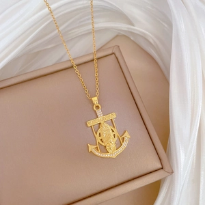 Detail of gold anchor cross pendant with full diamond inlay on a soft silk background