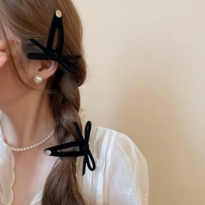Detail of black velvet bow hair clip with gold metal button on lace-clad model