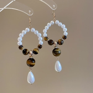 Detail view of vintage tiger eye stone and pearl drop earrings with silver hooks