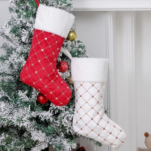 Red and white sequin Christmas stockings with faux fur trim hanging on a snowy tree