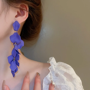 Detail shot of long purple resin petal tassel earrings on model with white lace top