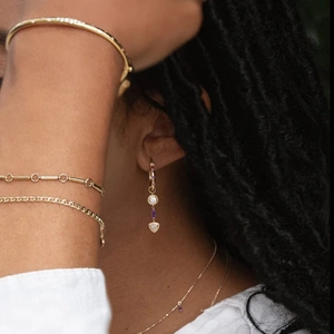 Detailed close-up of golden jewelry set with purple zircon stones on a female model