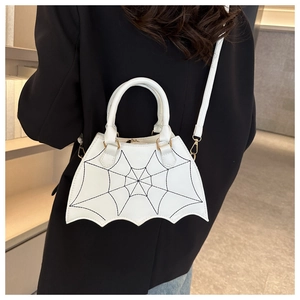 Detail of white bat-shaped crossbody bag with black spider web stitching on black suit