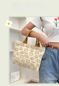 Detail of canvas tote bag featuring cartoon bear patterns and brown woven handles