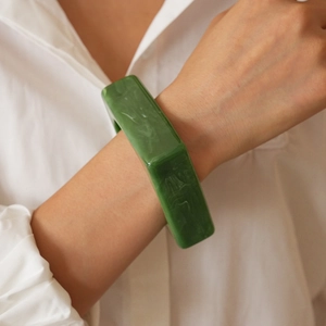 Close-up of green marble-patterned acrylic chunky bangle worn on wrist for fashion style
