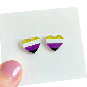 Gros plan de boucles d'oreilles cœur pailletées drapeau non binaire sur carte