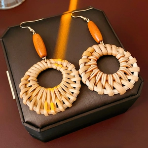 Détail des boucles d'oreilles bohèmes rondes en rotin tressé avec perle en bois et crochets