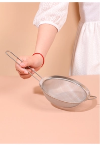 Close-up of stainless steel fine mesh strainer with wire handle in use in the kitchen