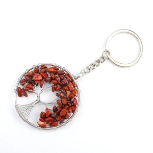 Macro detail of handmade silver wire-wrapped tree of life keychain with reddish stones