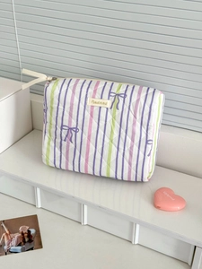 Detail of quilted purple stripe cosmetic bag with bow pattern and metal zipper closure