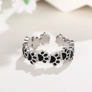 Makroaufnahme von silbernem offenem Ring mit schwarzen Emaille-Katzenpfotenmustern