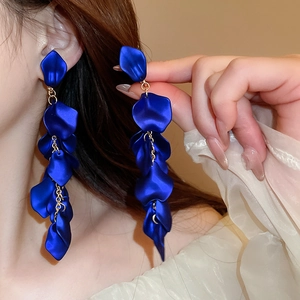 Close-up of elegant deep blue rose petal fringe earrings worn by a model in soft light