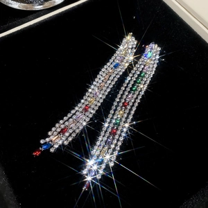 Macro shot of colorful zircon tassel earrings on black velvet background showing sparkle