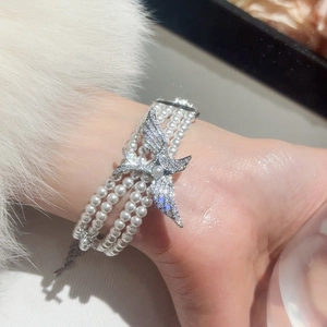 Vue détaillée d'un bracelet de perles multicouche avec un charm papillon en zircon brillant