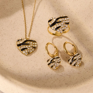 Detailed set of gold heart earrings, necklace, and ring with zebra enamel and zircons